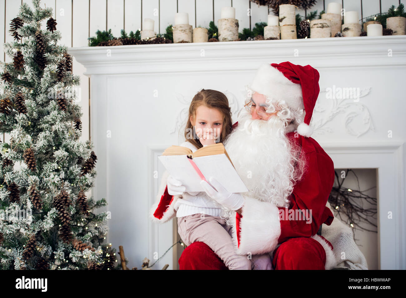 Bambino felice ragazza abbracciando Santa la lettura del libro e risate Foto Stock