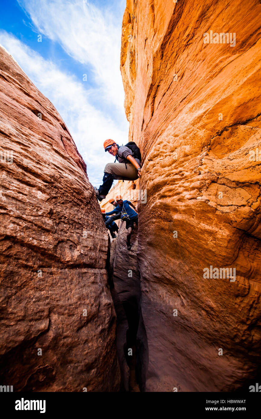 Un gruppo di giovani uomini al lavoro attraverso Raven, uno slot canyon nel Escalante, Utah Foto Stock