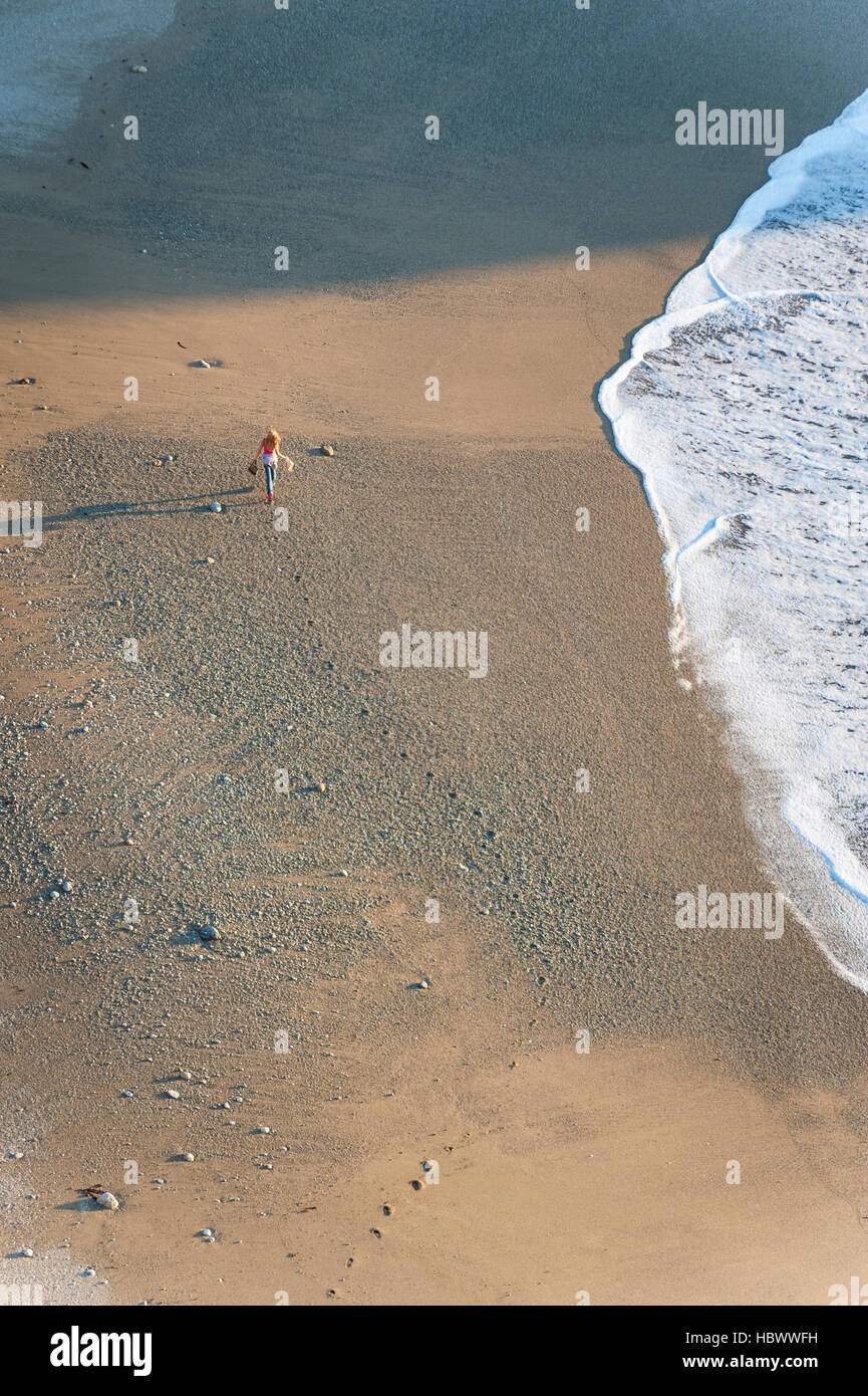 Donna che cammina da sola / da sé sulla spiaggia sulla costa della California - Vista da sopra, Julia Pfeiffer Burns State Park. Foto Stock