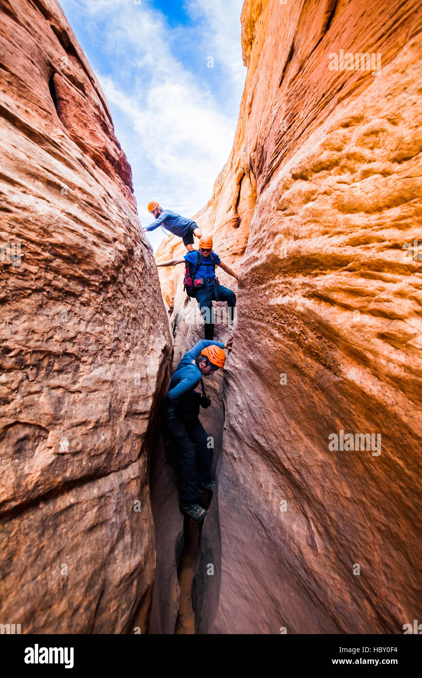 Un gruppo di giovani uomini al lavoro attraverso Raven, uno slot canyon nel Escalante, Utah Foto Stock