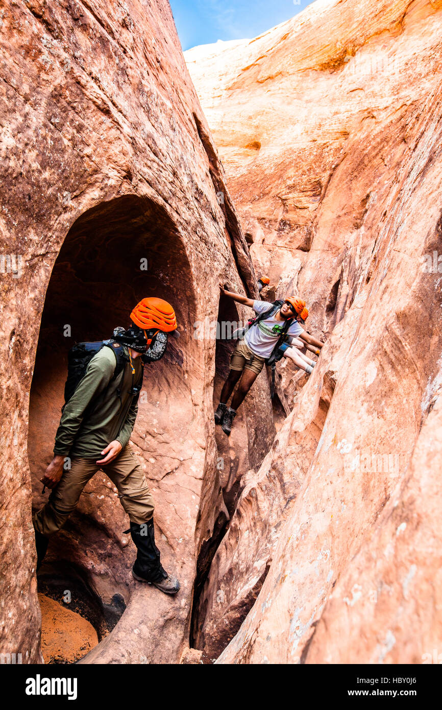 Un gruppo di giovani uomini al lavoro attraverso Raven, uno slot canyon nel Escalante, Utah Foto Stock