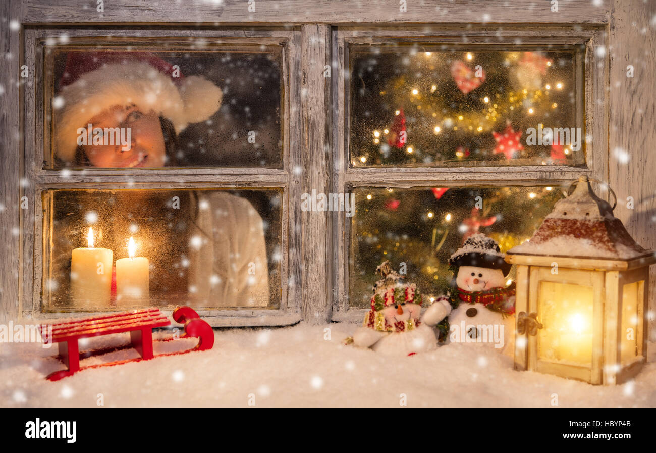 Atmosferica nella finestra di Natale con Santa ragazza guardando fuori di  vetro. Concetto di sera di Natale Foto stock - Alamy