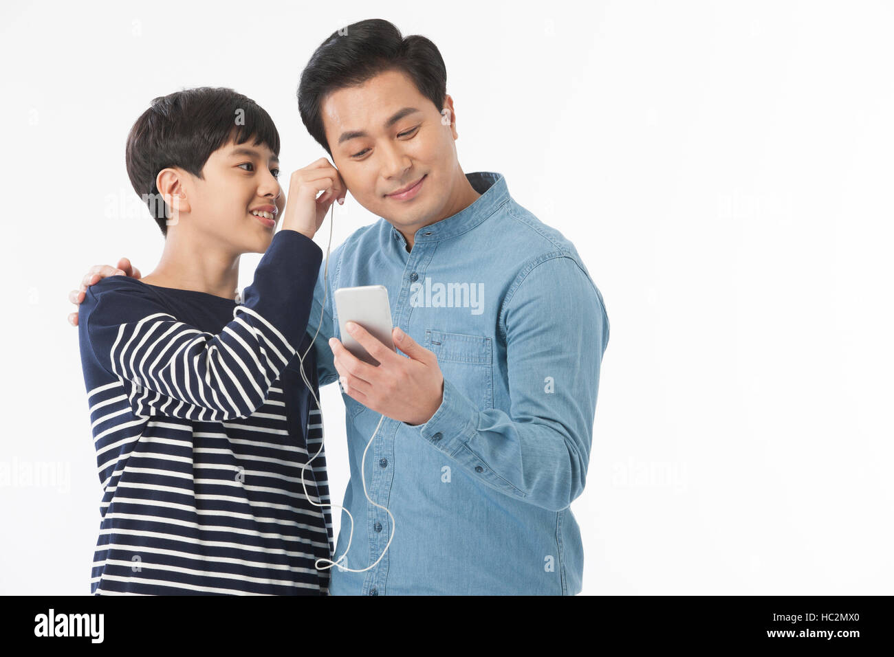 Sorridente padre e figlio adolescente ascoltare musica sullo smartphone Foto Stock