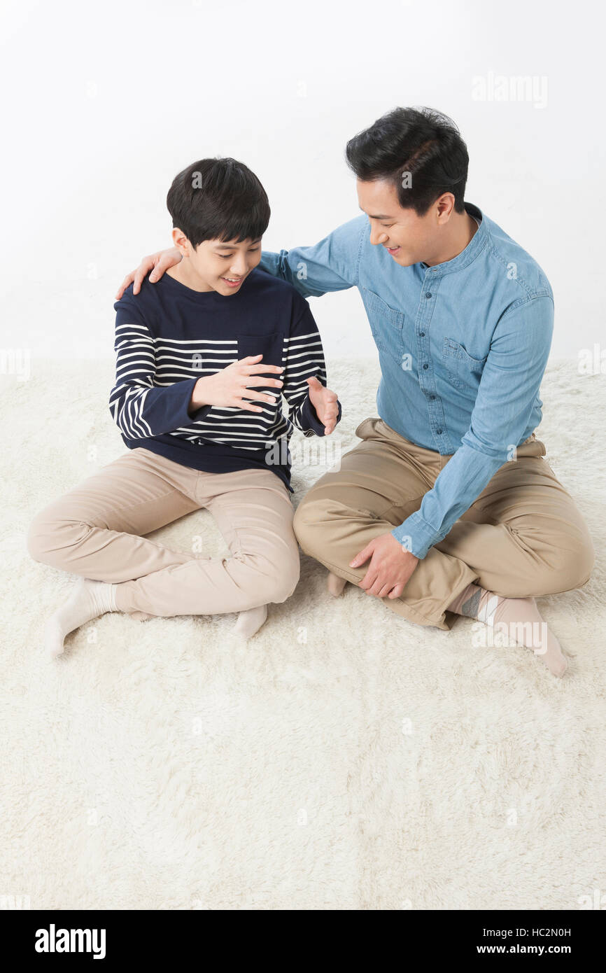 Sorridente padre e figlio adolescente seduta di parlare faccia a faccia Foto Stock