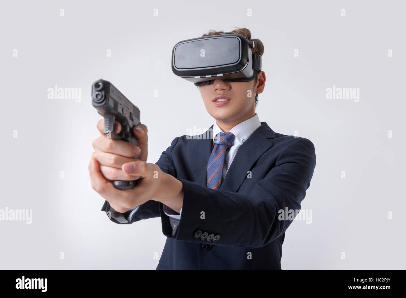 Giovane imprenditore indossando la realtà virtuale del livellamento della cuffia una pistola Foto Stock