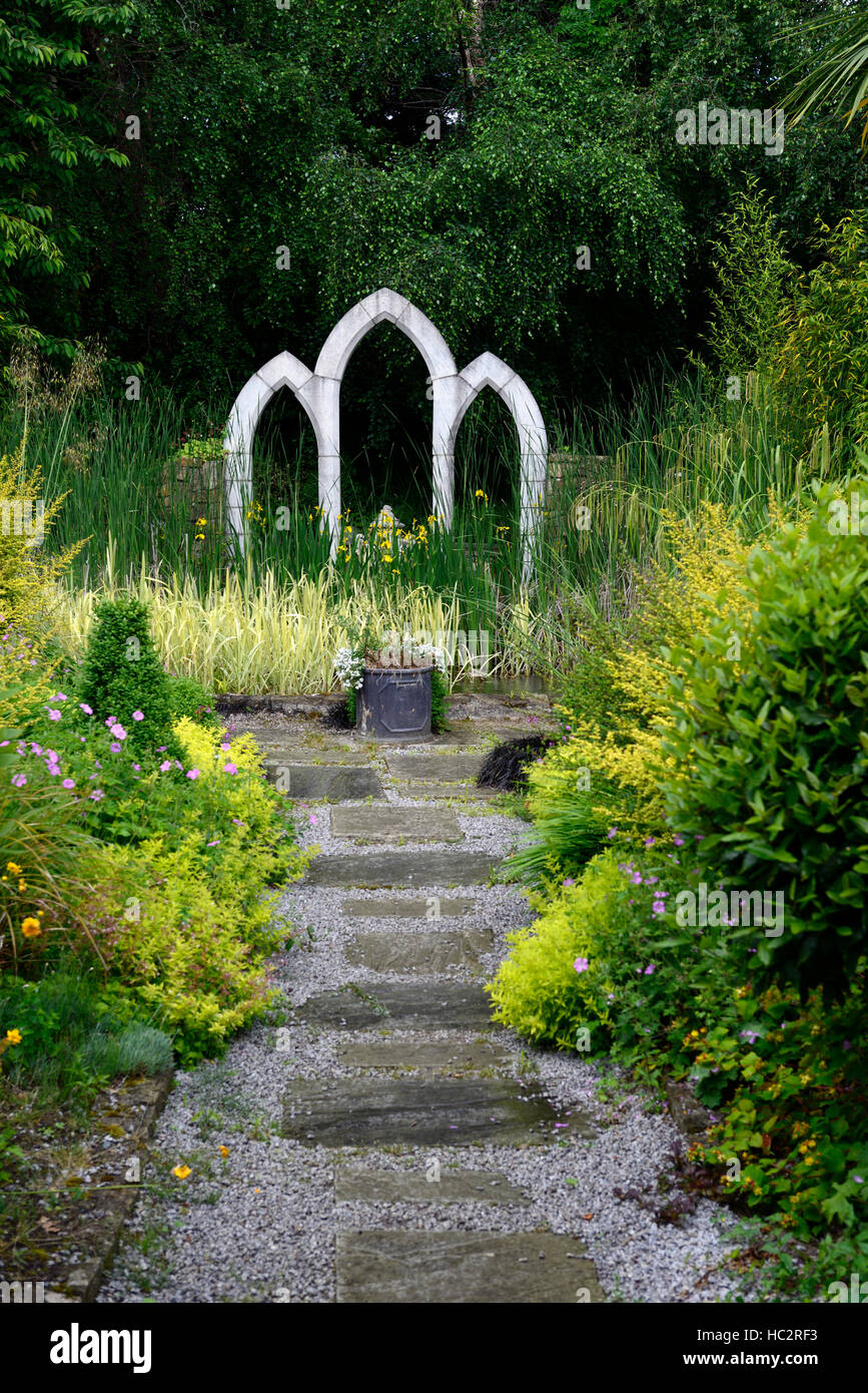 Garden design percorso leader di piombo arcata in pietra ad arco centro windows centrato includono giardinaggio foglie verde fogliame floreale RM Foto Stock