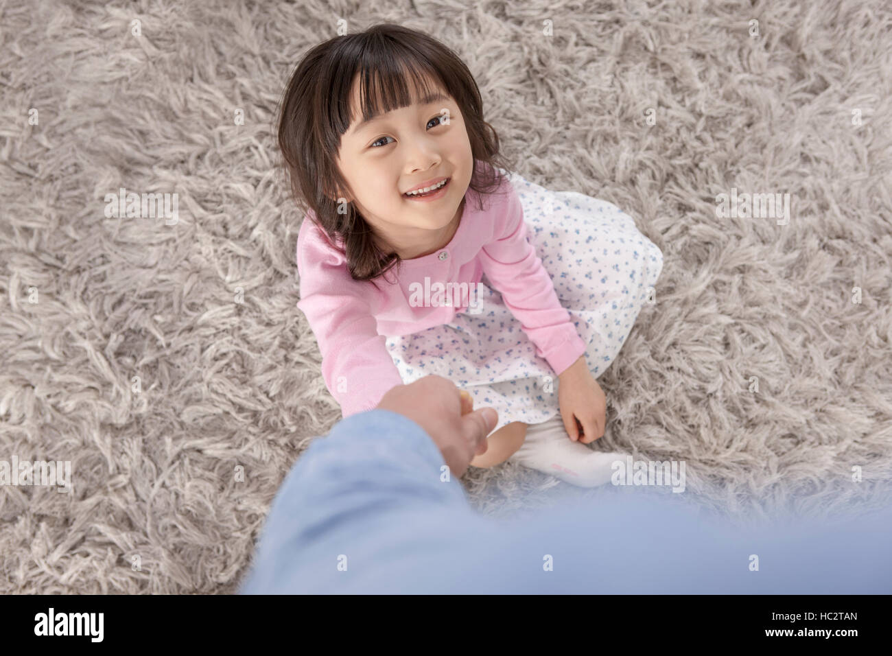 Angolo di alta vista sorridente sei-anno-vecchia ragazza coreana tenendo la sua mano del padre Foto Stock