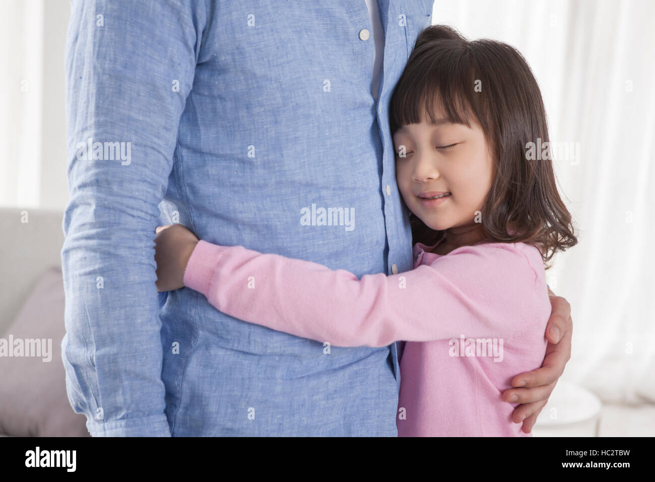 Sei-anno-vecchio sorridente ragazza coreana abbracciando il padre con gli occhi chiusi Foto Stock