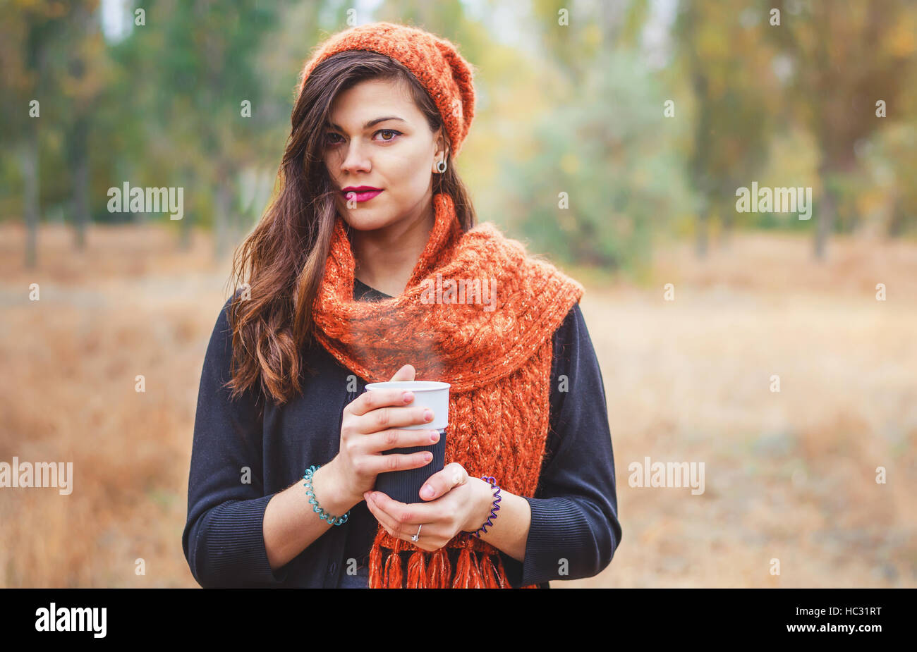 Giovane bella ragazza con una tazza di caffè (TEA) per una passeggiata nel parco all'aperto. Autunno meteo. Foto Stock