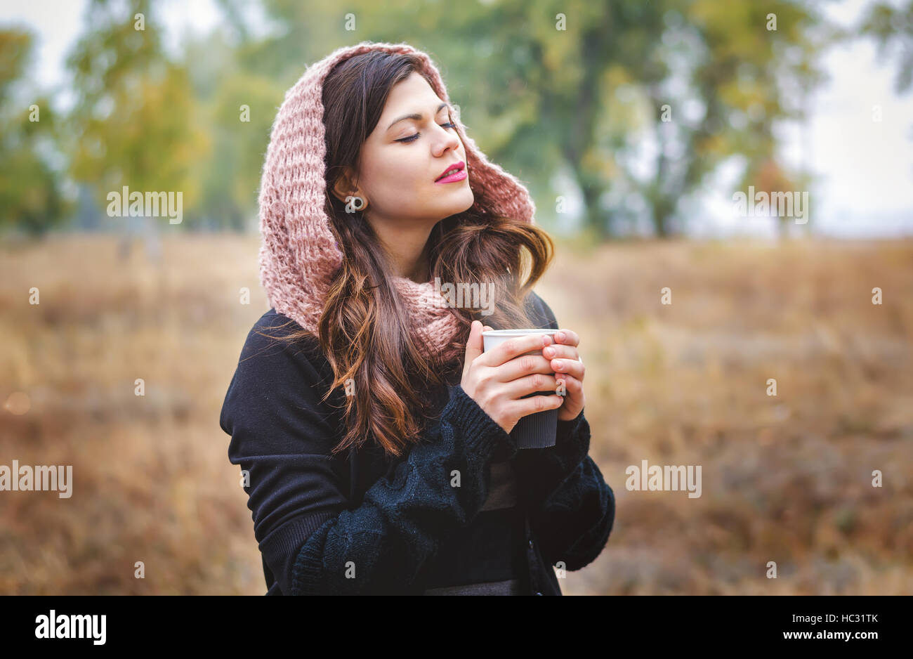 Giovane ragazza di sognare con una tazza di caffè (TEA) per una passeggiata nel parco all'aperto. Autunno meteo. Foto Stock