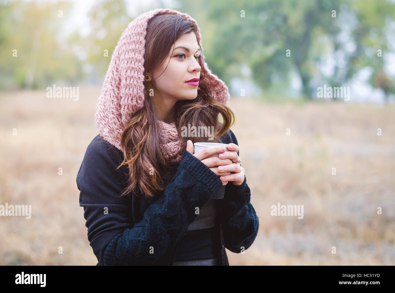 Ritratto di un grave ragazza giovane con una tazza di caffè (TEA), una sciarpa in autunno park. Foto Stock