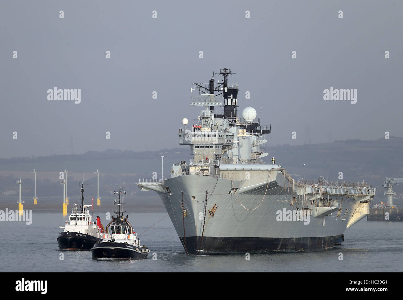 La Royal Navy dell ex portaerei HMS illustre è trainato fuori del porto di Portsmouth voce per un bagno turco scrapyard. Foto Stock