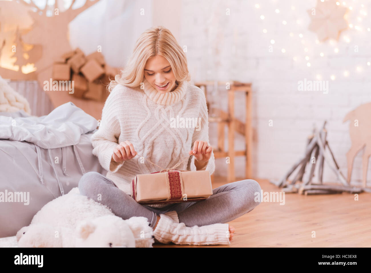 Positivo donna curiosa apertura di una scatola di Natale Foto Stock