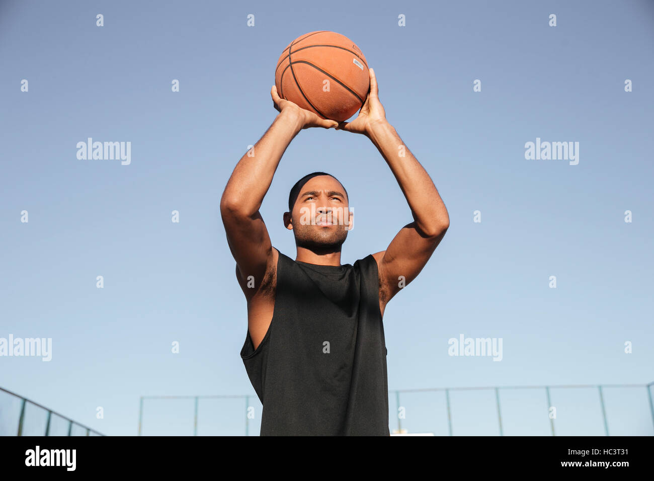 Ritratto di giovane africano uomo sportivo jumping con basketball presso il parco giochi Foto Stock