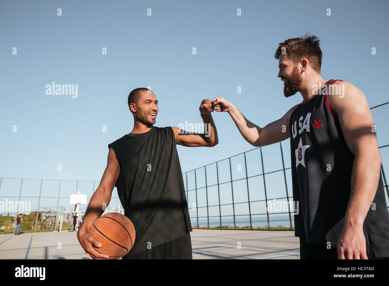 Due lieti di sportivi fist bumping prima di iniziare il gioco di basket presso il parco giochi Foto Stock