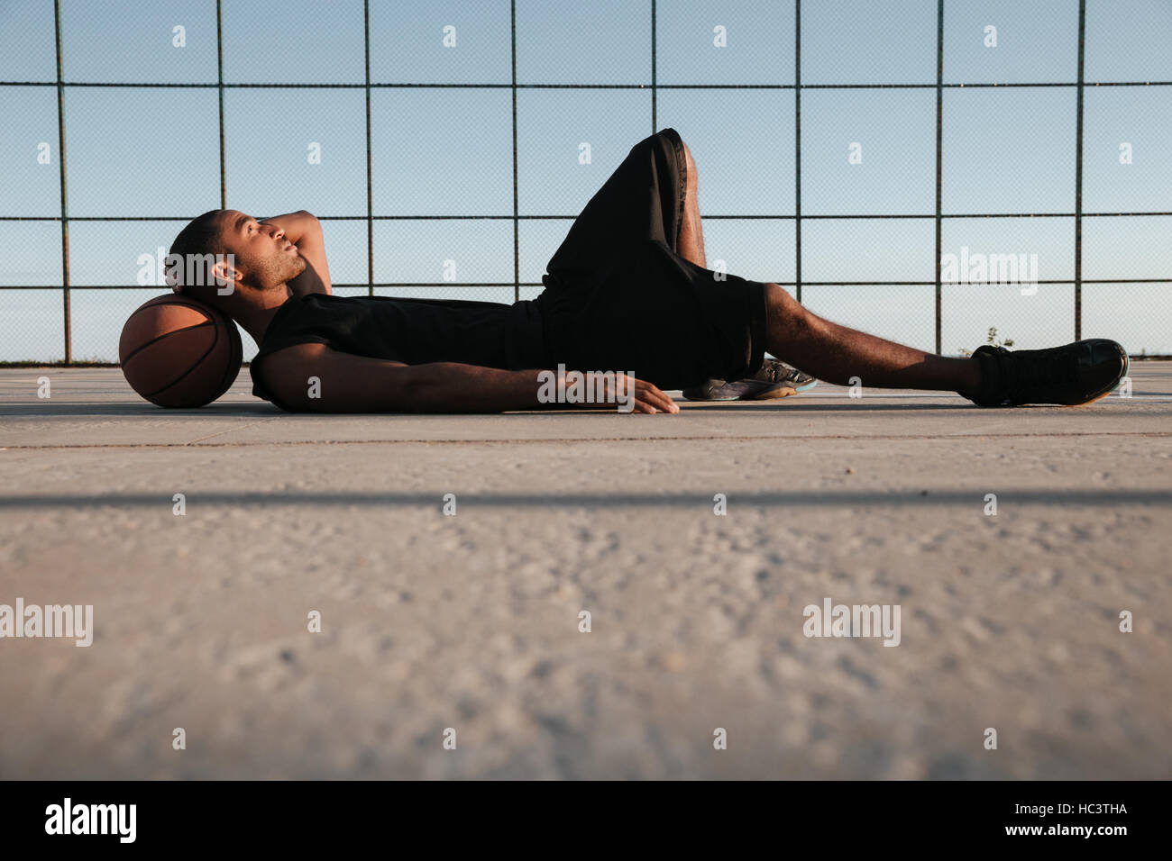 A piena lunghezza Ritratto di una giovane afro american sports uomo disteso sul parco giochi con basket Foto Stock