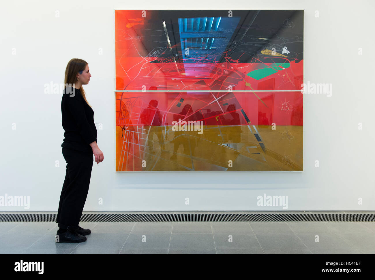 Le gallerie a serpentina, Londra, Regno Unito. Il 7 dicembre 2016. Mostra di dipinti e disegni dal rinomato architetto Zaha Hadid (1950-2016) presso la Serpentine Sackler Gallery. Un membro del personale galleria esamina di Berlino del 2000, 1988, con galleria visitatori si riflette nell'alta brillantezza superficie acrilica. Credito: artsimages/Alamy Live News. Foto Stock