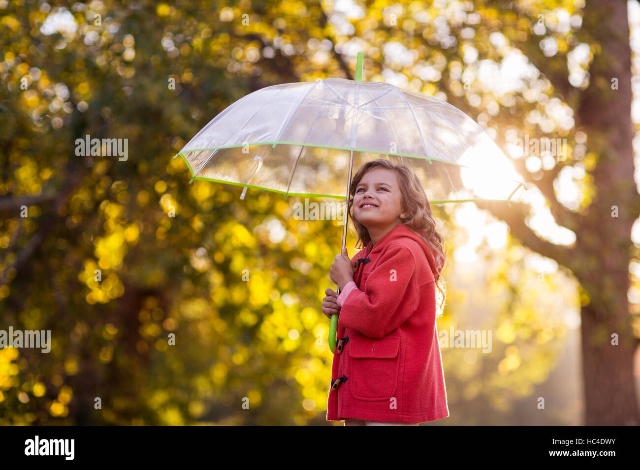 Vista laterale della ragazza con ombrello contro alberi Foto Stock