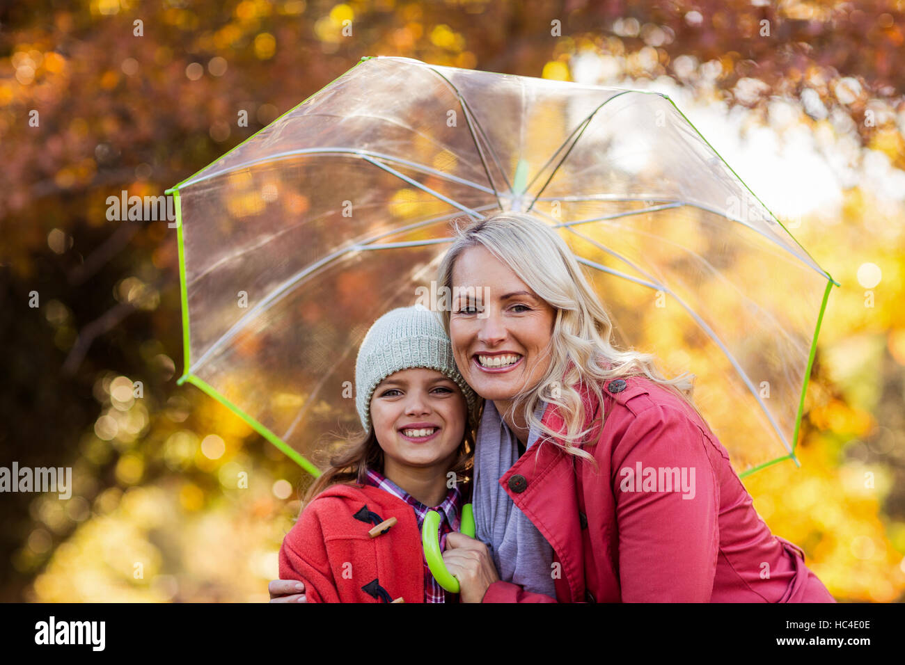 Madre e figlia abbracciando tenendo ombrello Foto Stock