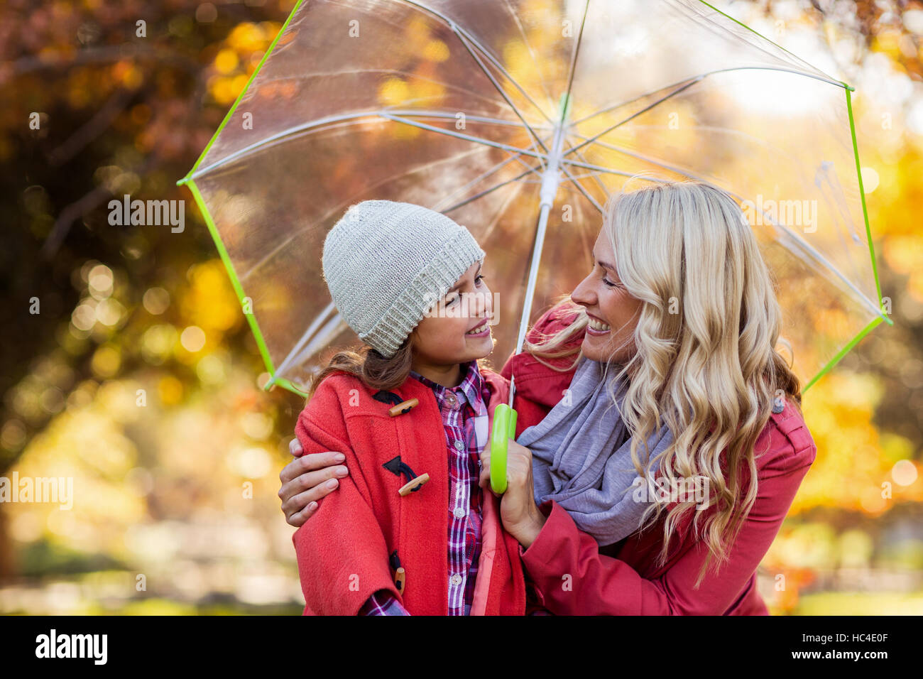 Felice madre e figlia ombrello di trattenimento in posizione di parcheggio Foto Stock