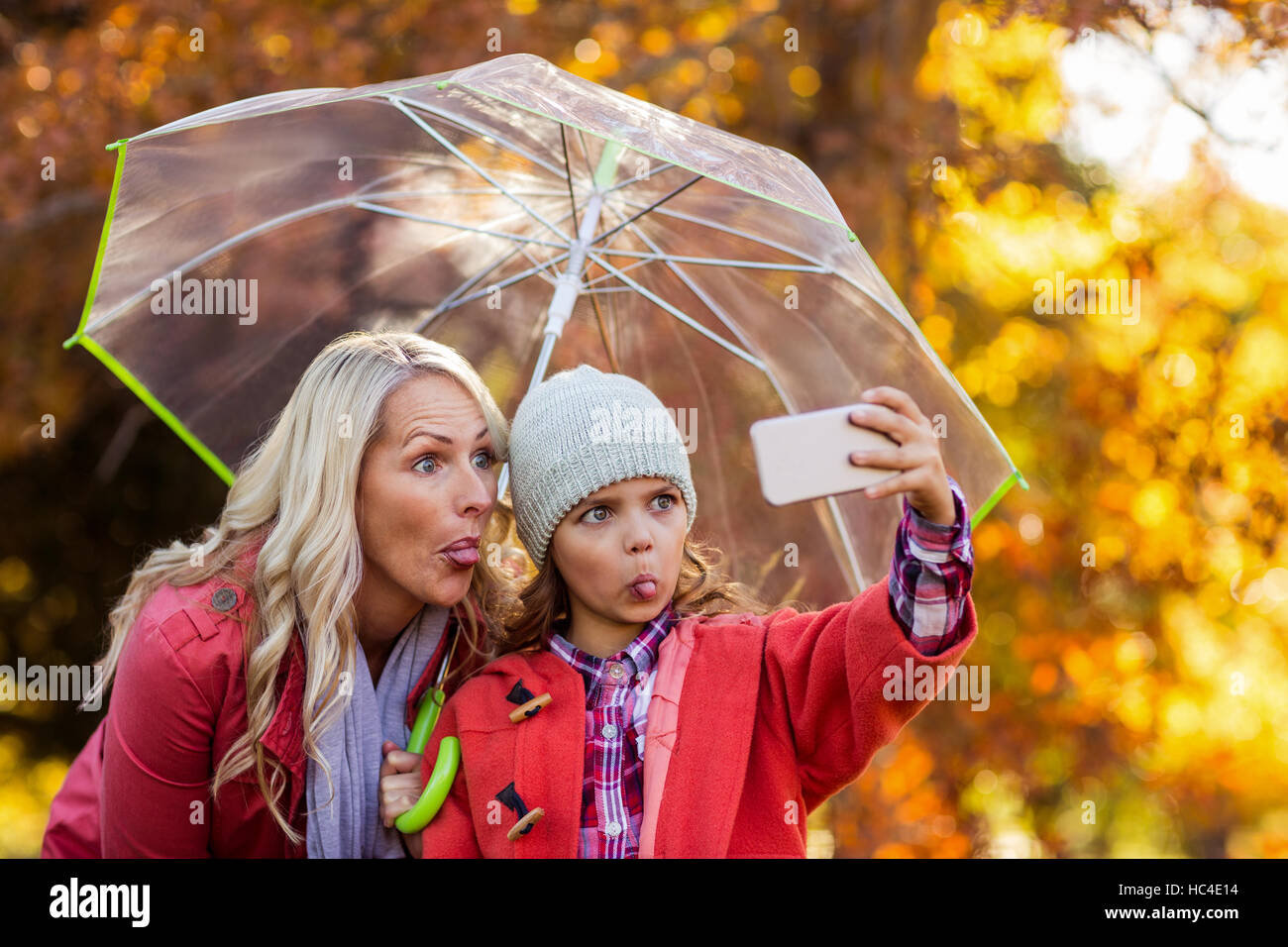 Ragazza tenendo selfie con la madre in posizione di parcheggio Foto Stock