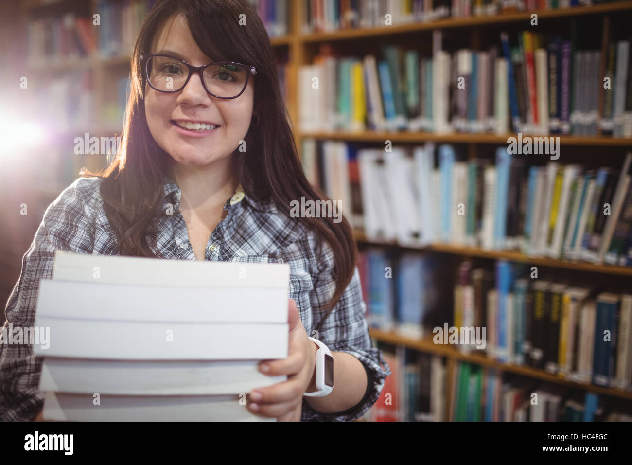Ritratto di studenti di sesso femminile in possesso di una pila di libri in biblioteca Foto Stock