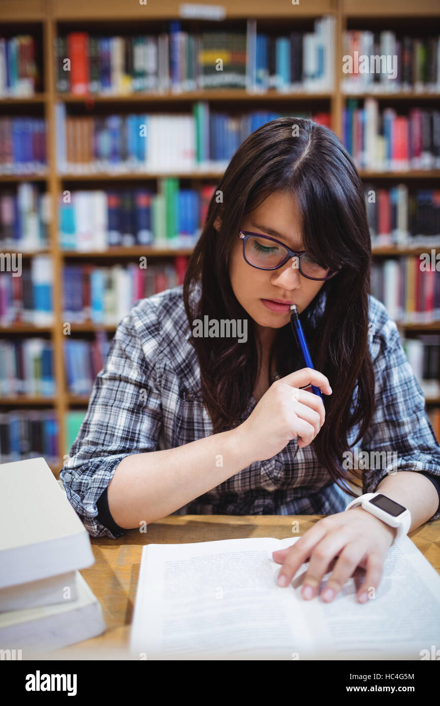 Studentessa guardando le note in biblioteca Foto Stock