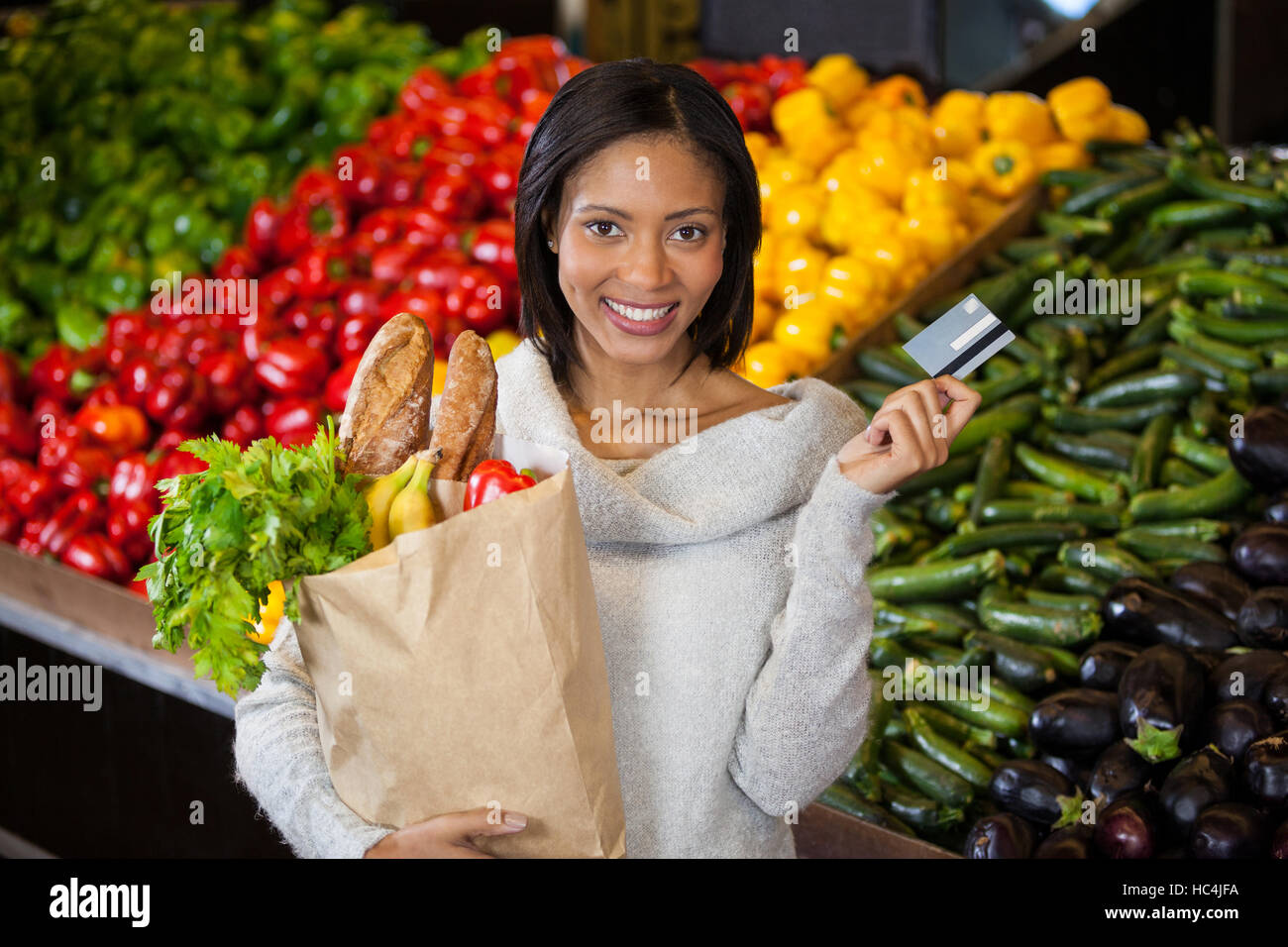 Donna che mantiene la carta di credito e negozio di generi alimentari in borsa Foto Stock