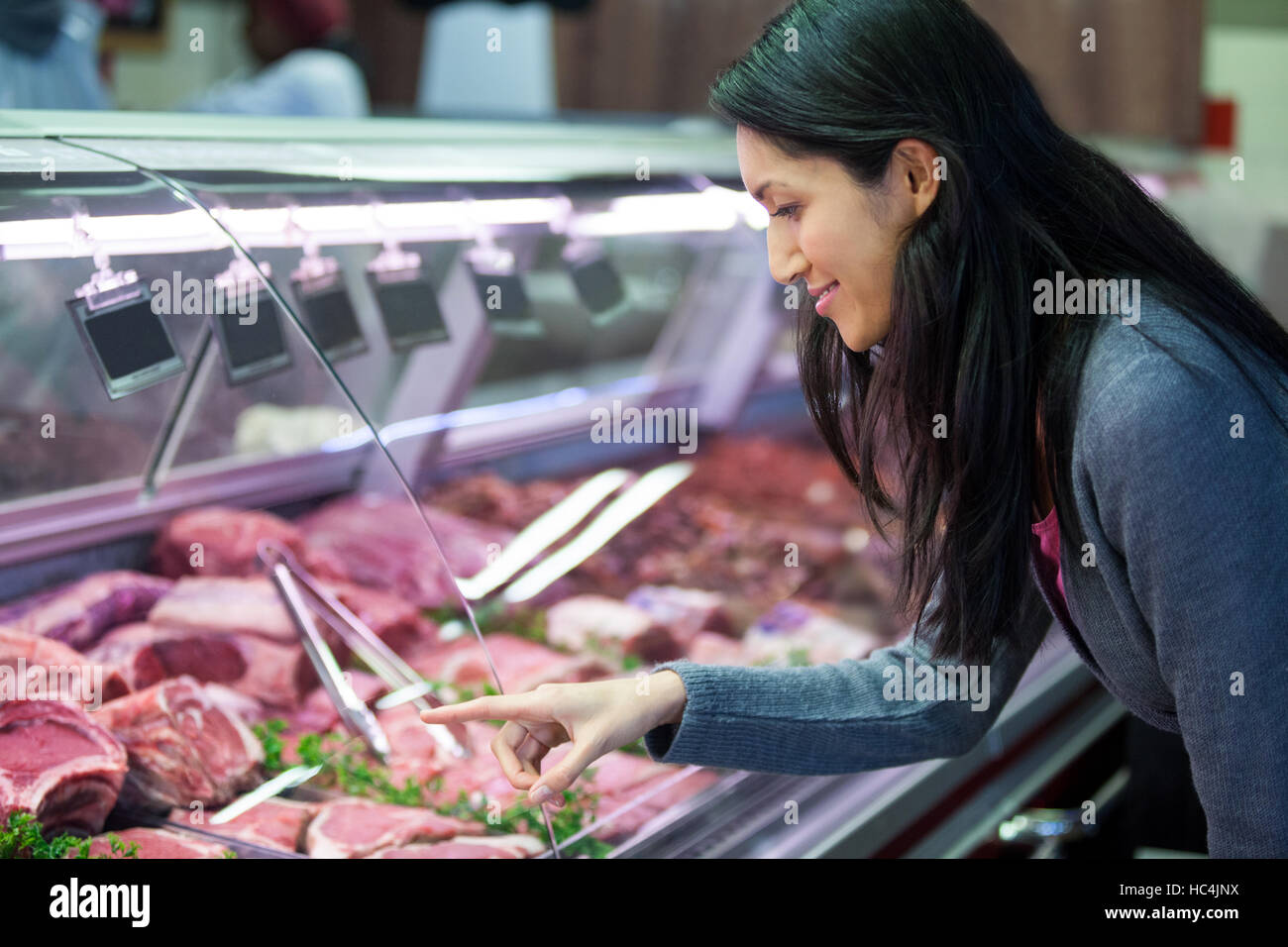 Donna puntando alla carne nel display Foto Stock