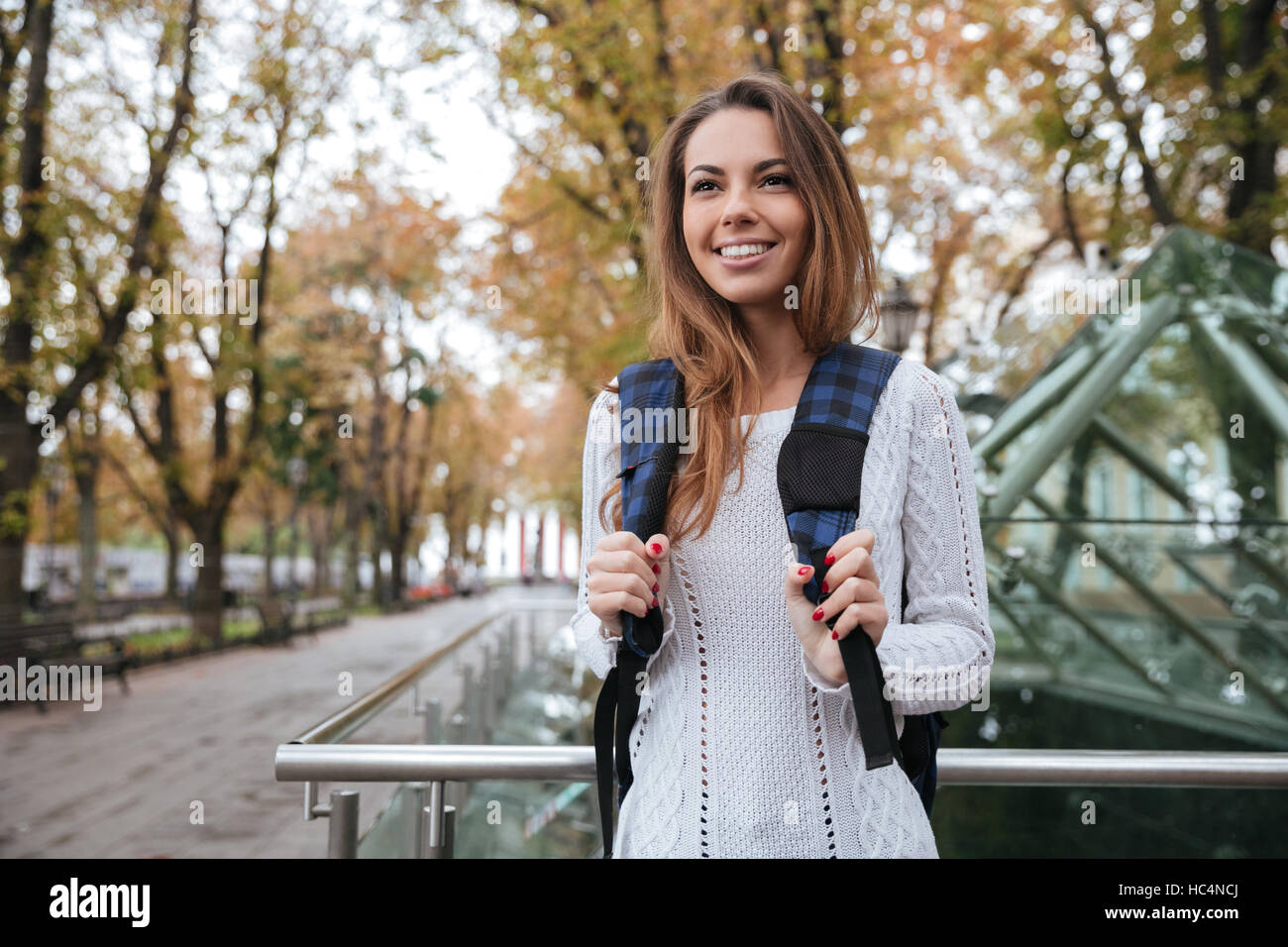 Allegro affascinante giovane donna con zaino passeggiate nel parco Foto Stock