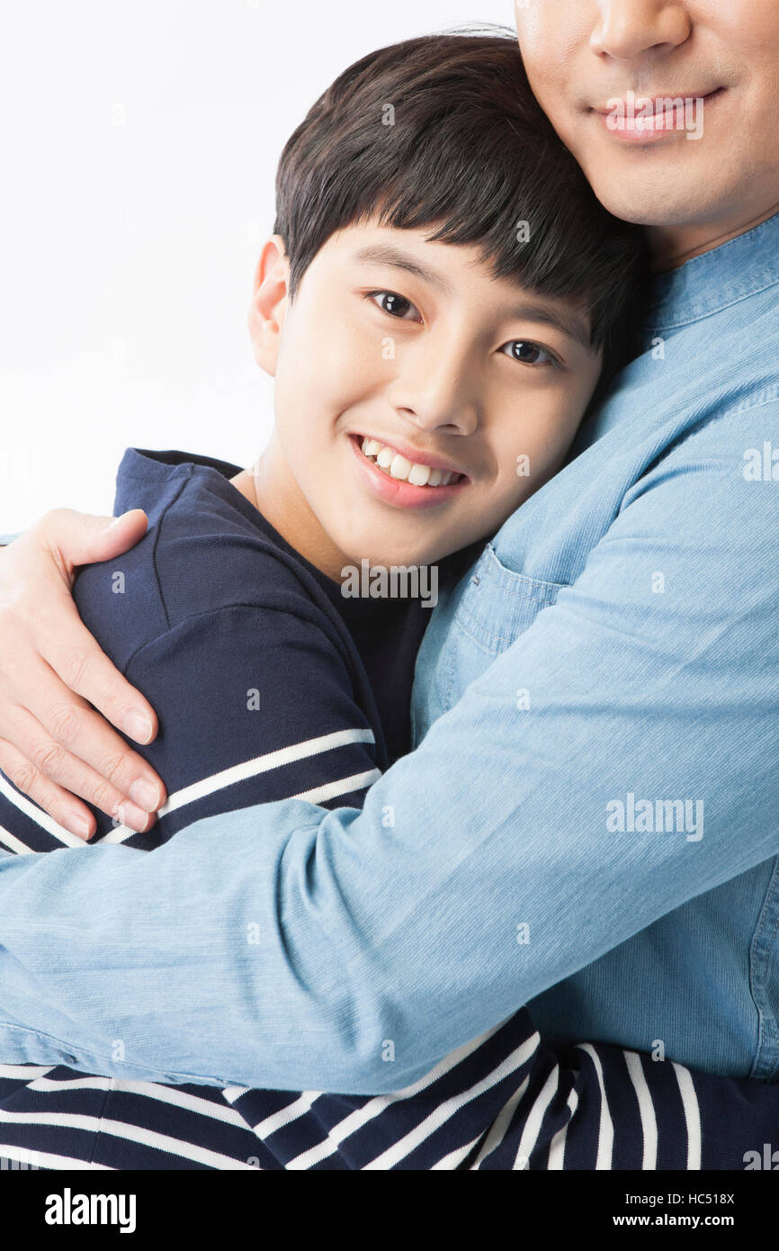Vista laterale ritratto di sorridente figlio adolescente abbraccia il suo padre Foto Stock
