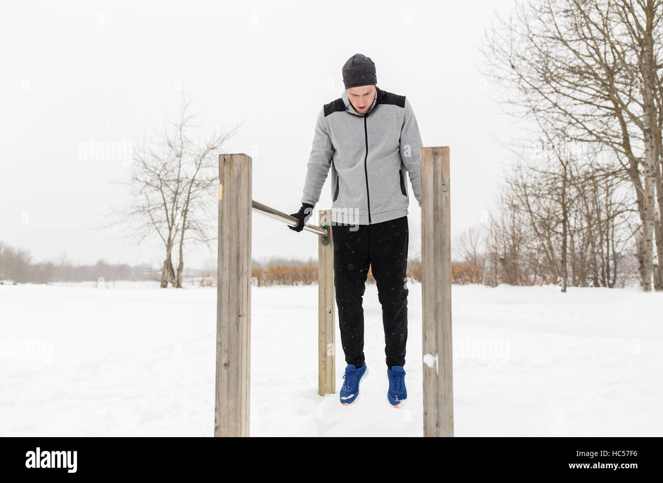 Giovane uomo esercitando sulle barre parallele in inverno Foto Stock