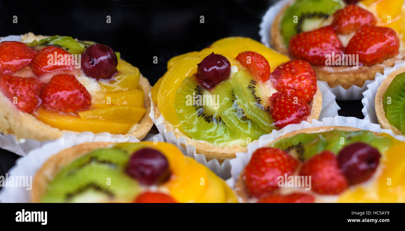 Appena sfornati vetrato crostate di frutta isolati contro uno sfondo nero. Foto Stock
