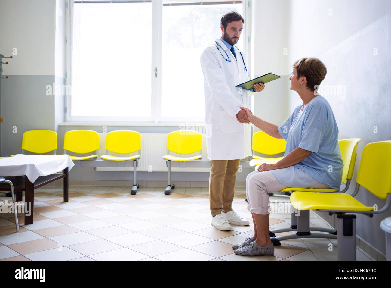 Medico agitando la mano con il paziente in sala di attesa Foto Stock