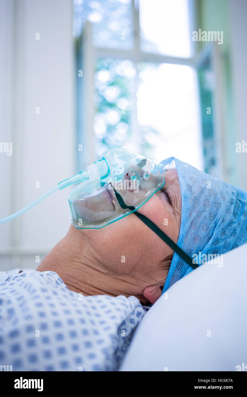 Paziente che indossa la maschera di ossigeno giacente sul letto di ospedale Foto Stock