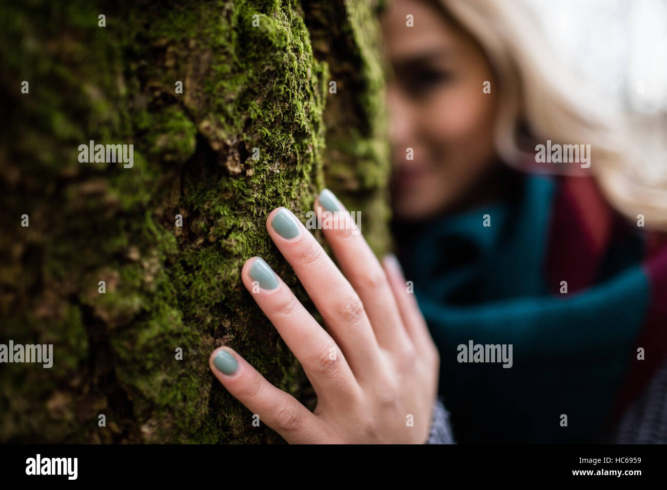 Donna nascondersi dietro a tronco di albero Foto Stock