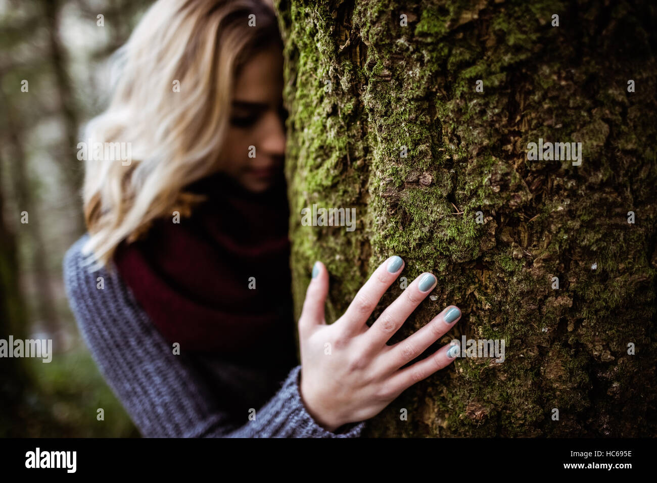 Donna appoggiata sul tronco di albero Foto Stock
