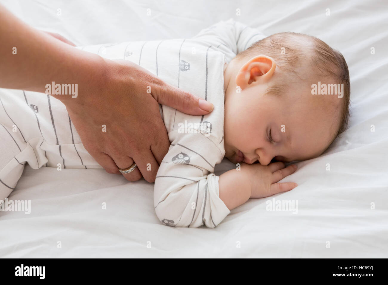 La mamma di mettere il bambino a dormire nel letto per bambino Foto Stock