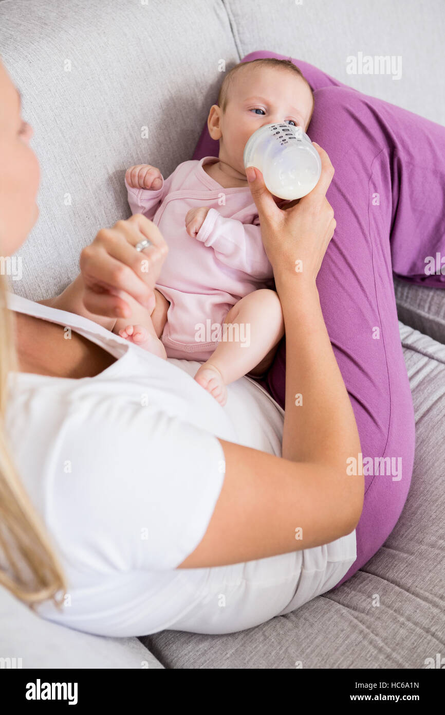 La madre del bambino di alimentazione con bottiglia di latte in salotto Foto Stock
