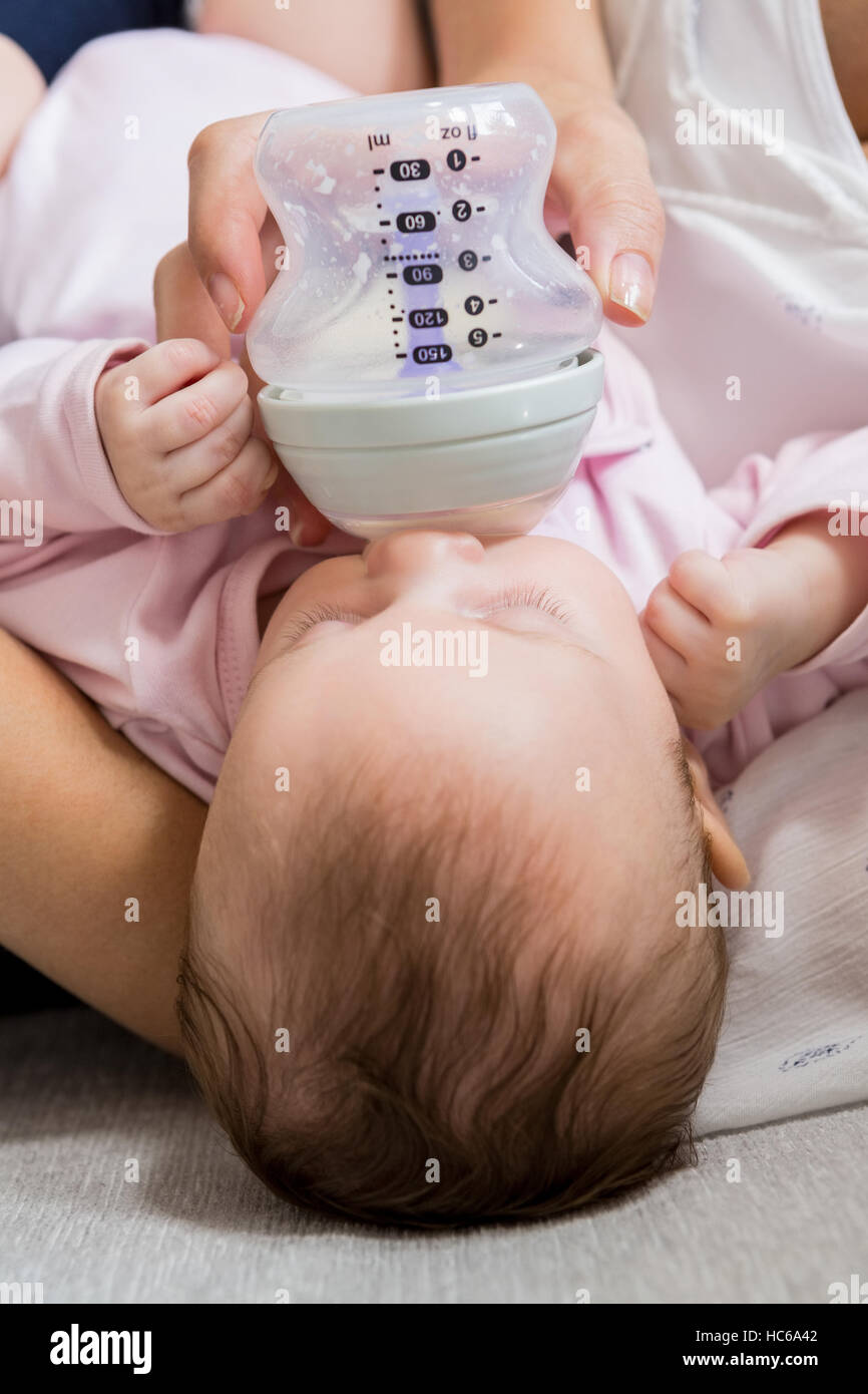 La madre del bambino di alimentazione con bottiglia di latte in salotto Foto Stock