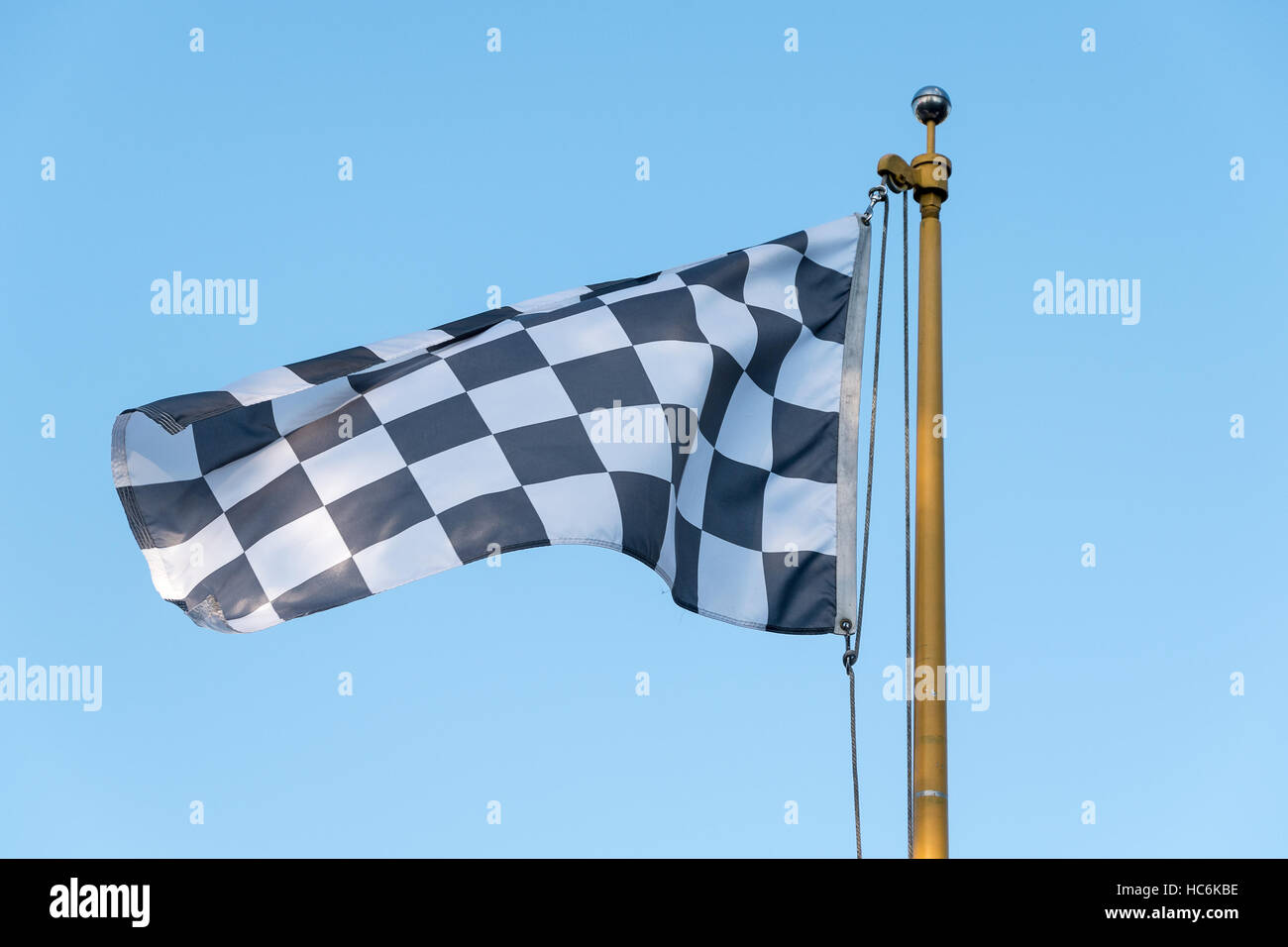 Bandiera a scacchi soffia nel vento su un palo di bandiera Foto Stock