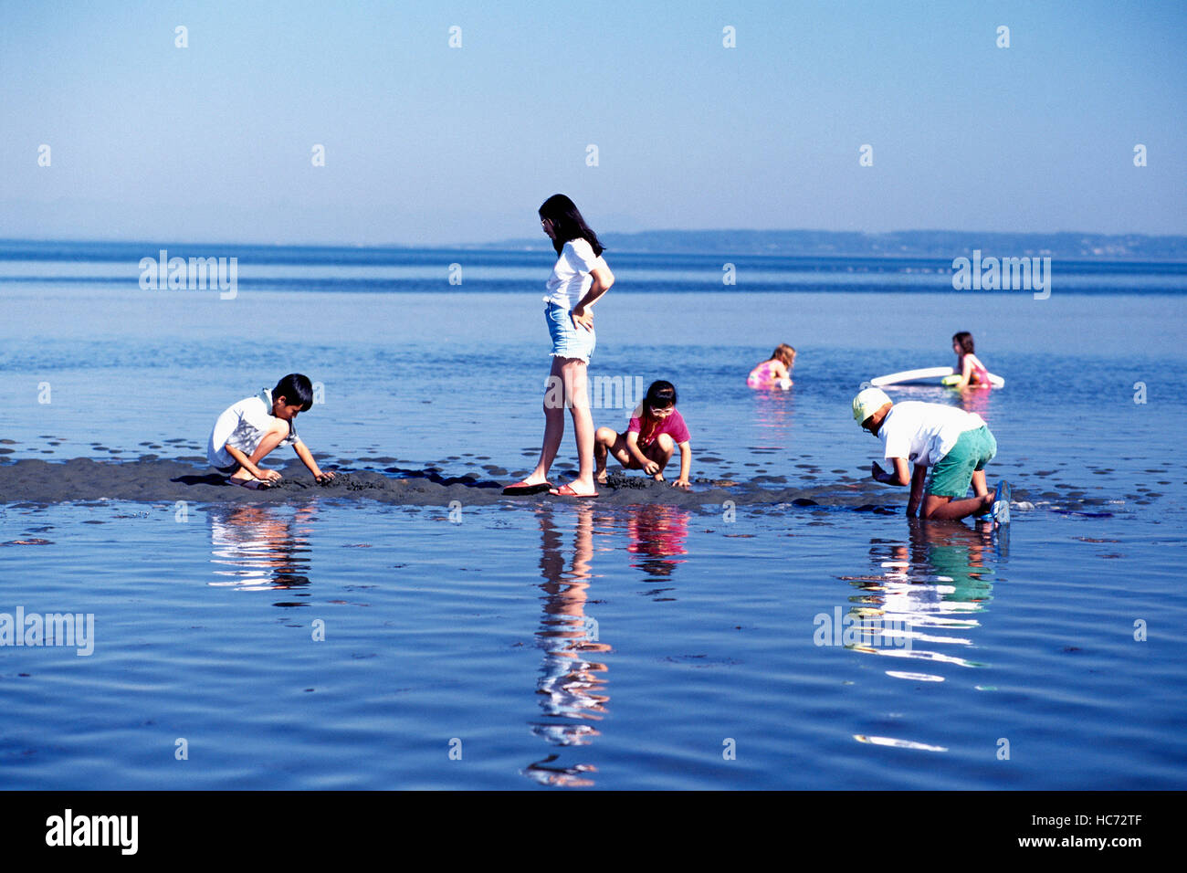 I bambini a giocare all'aperto in acqua dell'Oceano Pacifico e la baia di confine del Parco Regionale del Delta, BC, British Columbia, Canada Foto Stock