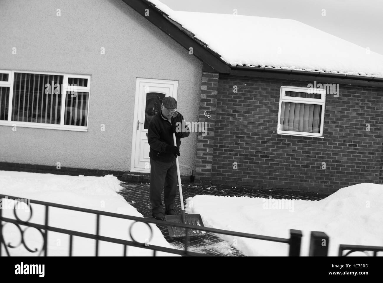 Anziano gentiluomo spalare la neve con una pala per cancellare il suo percorso e la trasmissione Foto Stock