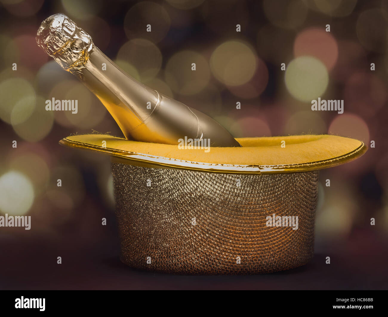 Bottiglia di champagne nel golden top hat più sfocato sfondo luminoso Foto Stock