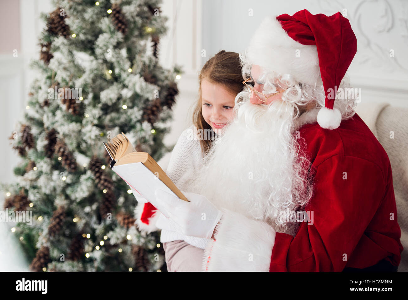 Bambino felice ragazza abbracciando Santa la lettura del libro e risate Foto Stock