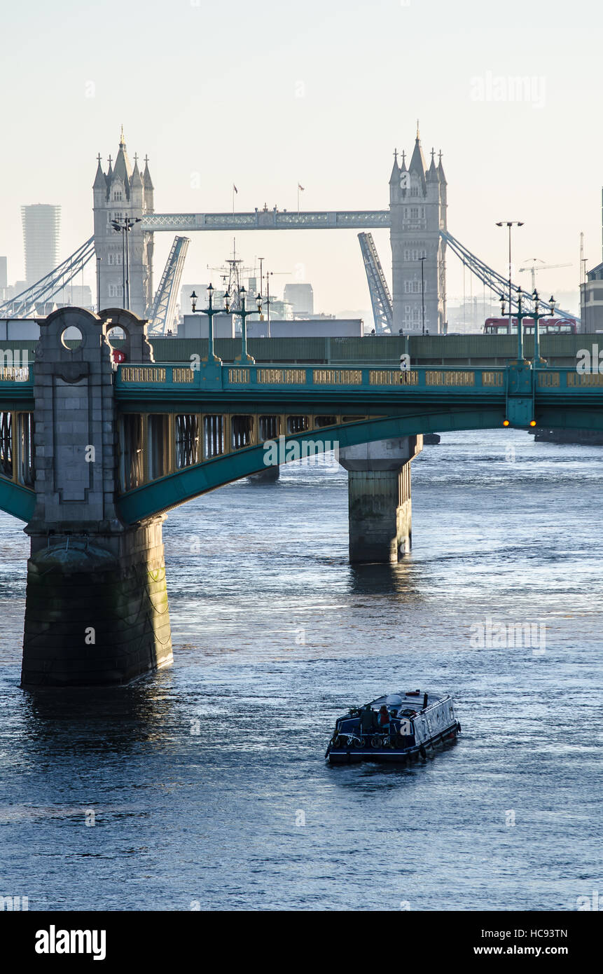 Barca stretta sul Tamigi a Londra sotto i ponti. Una vista ventosa e nebbiosa del mattino sul Southwark Bridge verso il Tower Bridge Foto Stock