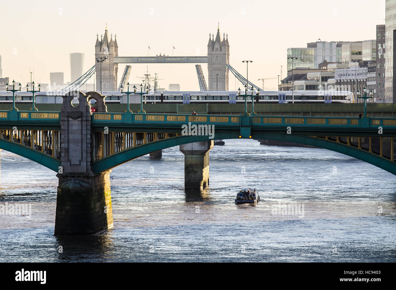 Barca stretta sul Tamigi a Londra sotto i ponti. Una vista ventosa e nebbiosa del mattino sul Southwark Bridge verso il Tower Bridge Foto Stock
