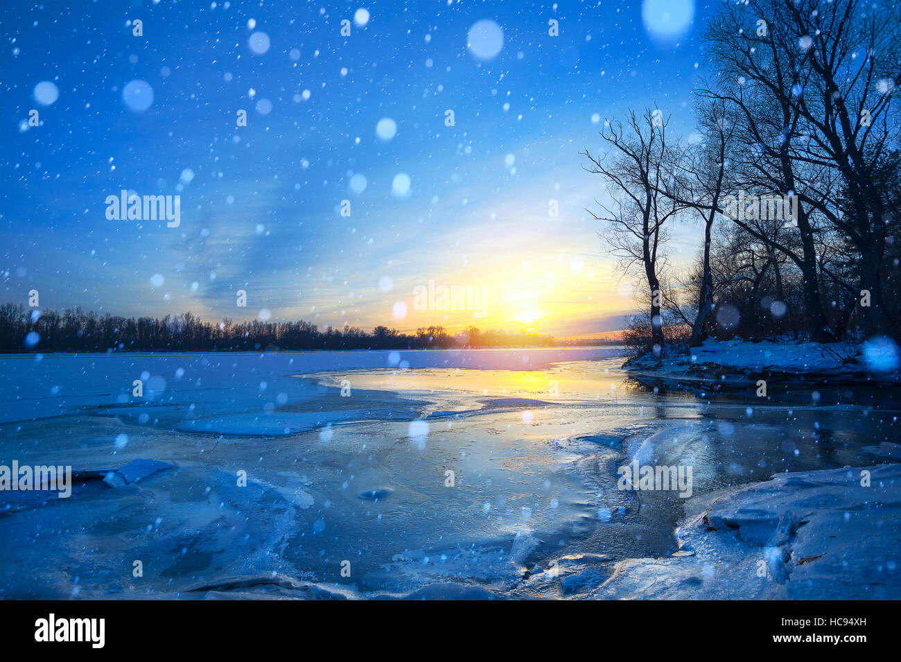 Paesaggio invernale panorama; Tramonto sulla sponda di un fiume congelato; ghiaccio e neve Foto Stock