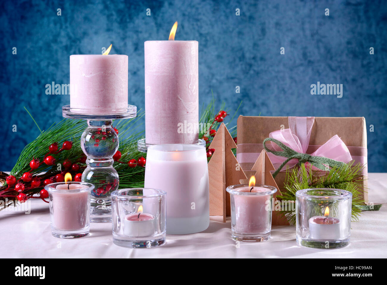 Festive glamour natale vacanze messa in tavola con candele rosa, dono contro uno sfondo blu. Foto Stock