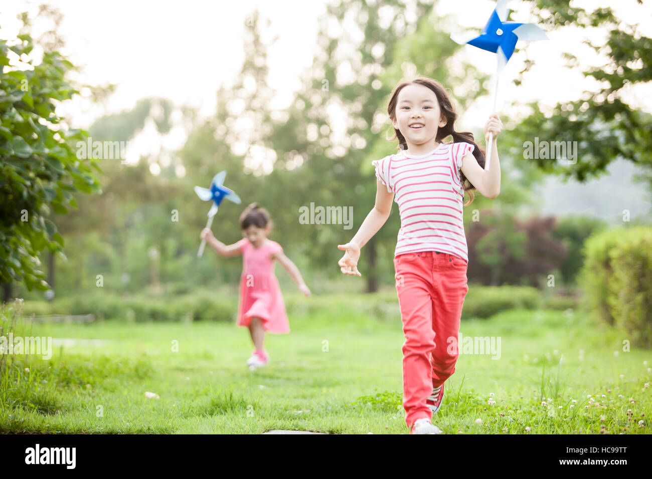Due ragazze sorridenti con pinwheels in esecuzione sul campo Foto Stock